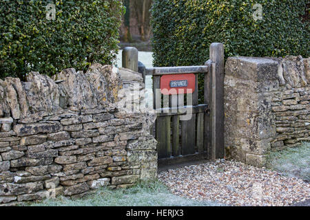 Ein Tor aus Holz Tor am Eingang zum Dorf Hausgarten mit einem privaten Zeichen auf der Vorderseite. Stockfoto