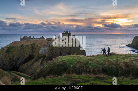 Zwei Fotografen erfassen Sie einen Winter-Sonnenaufgang über Dunnottar Castle, in der Nähe von Stonehaven im Nordosten Schottlands Stockfoto