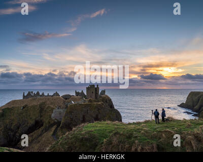 Zwei Fotografen erfassen Sie einen Winter-Sonnenaufgang über Dunnottar Castle, in der Nähe von Stonehaven im Nordosten Schottlands Stockfoto