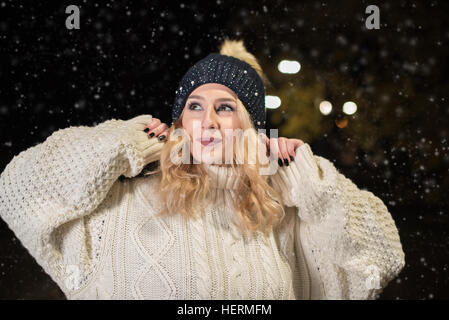 Junge Frau im Strickpullover im Schnee Stockfoto