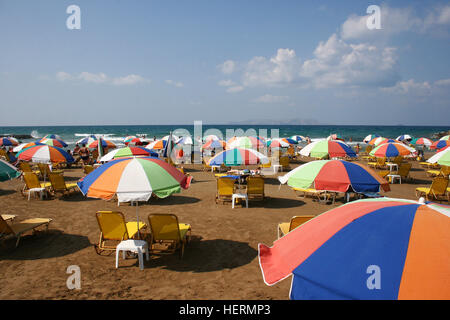 Regenbogenfarbenen Sonnenschirme in Reihen an einem Strand auf Kreta Stockfoto