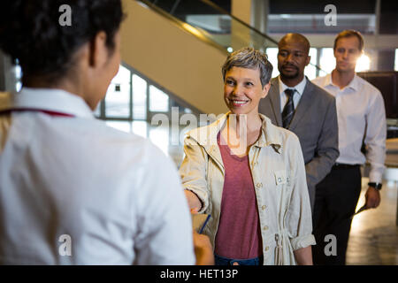 Frau, die Übergabe ihrer Bordkarte an das weibliche Personal am Flughafen-terminal Stockfoto