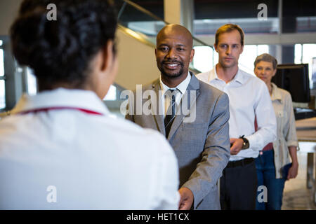 Geschäftsmann, die Übergabe seiner Bordkarte an das weibliche Personal am Flughafenterminal Stockfoto