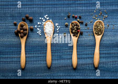 Gewürze auf Holzlöffel auf blauen Holztisch Stockfoto