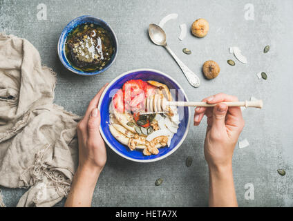 Blaue Schale mit gesunden vegetarischen Zutaten für das Frühstück in Frauenhand Stockfoto