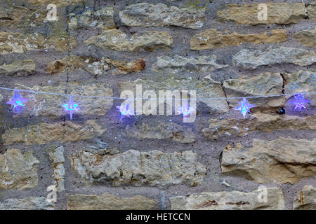 Blaue Sterne Lichterketten auf einer Steinmauer Stockfoto