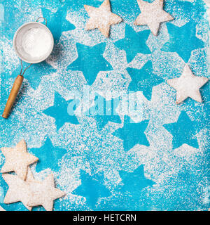 Herzförmige Kekse mit Puderzucker und Sieb, blauer Hintergrund Stockfoto