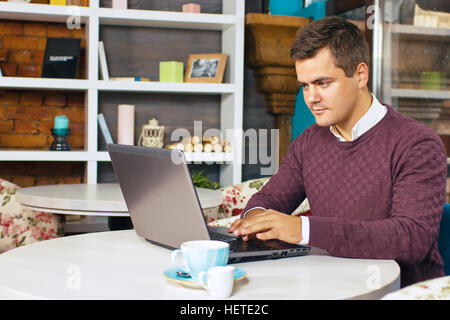 Glücklicher junger Mann lächelnd und arbeitet an seinem laptop Stockfoto