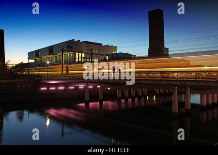 Sonnenuntergang in Amersfoort mit einem Zug auf einer Brücke mit dem "Eemhuis" im Hintergrund vorbei Stockfoto