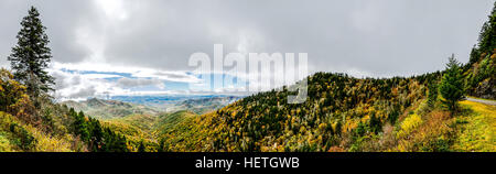 Sonne-Bursts durch dicke Wolken, ein Tal zu erhellen mit wechselnden Farben im Herbst Blätter bedeckt Stockfoto