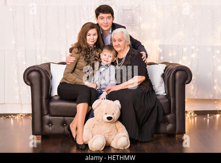 Erweiterte Familie auf Couch im Wohnzimmer sitzen und Lächeln in die Kamera Stockfoto