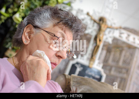 ältere Frau mit einem Kruzifix in den backgroud Stockfoto