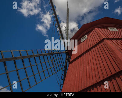 Close-up nach oben auf eine altmodische rote hölzerne Windmühle gegen blau-weißen Himmel in Strängnäs, Schweden Stockfoto