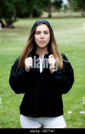 Blonde Kaukasische Frau im Park weiße Shorts und schwarze Jacke Stockfoto