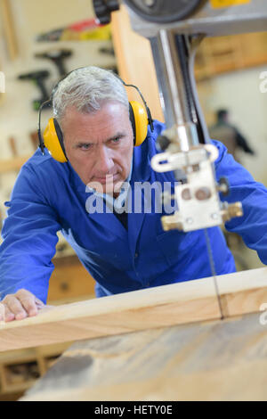 ältere Mann tragen von Gehörschutz bei der Verwendung der Tabelle sah Stockfoto