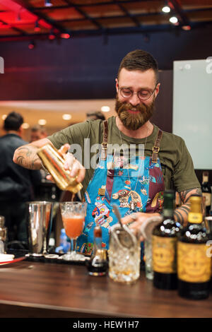 Kiew, UKRAINE - 30. Oktober 2016: Barmann Festival. Gut aussehend bärtige Hipster Barkeeper mit langem Bart und Schnurrbart mit lustigem Gesicht halten Shaker und machen alkoholische Cocktail. Stockfoto