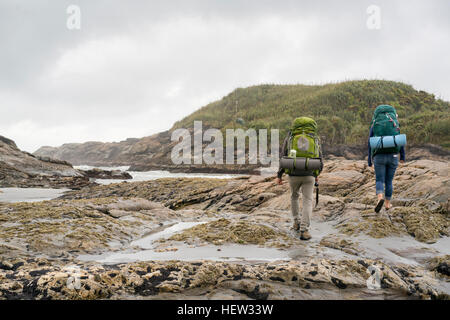 Junges Paar trekking über Gezeiten-Pools, hinten anzuzeigen, konstante Bay, Charleston, Südinsel, Neuseeland Stockfoto