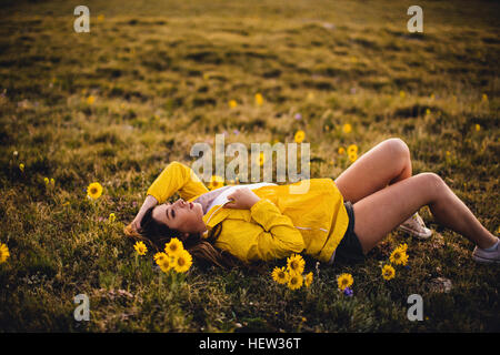 Frau liegt auf dem Rasen in Blüte gefüllt Wiese, Rocky Mountain Nationalpark, Colorado, USA Stockfoto