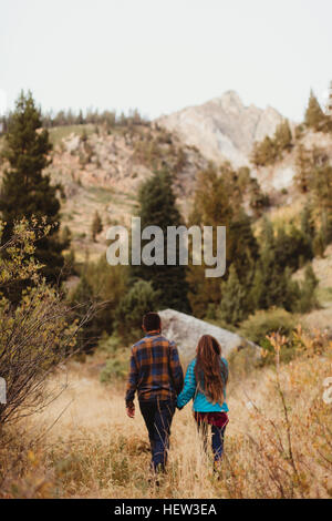 Junge Paare, die durch Feld, hintere Ansicht, Mineral King, Sequoia Nationalpark, Kalifornien, USA Stockfoto