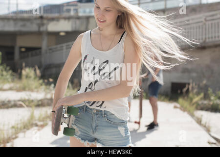 Skateboarder in Tank-Top mit Wild am Herzen Motto, Freunde im Hintergrund Stockfoto