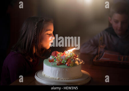 Mädchen bläst Kerzen auf Geburtstagskuchen Stockfoto