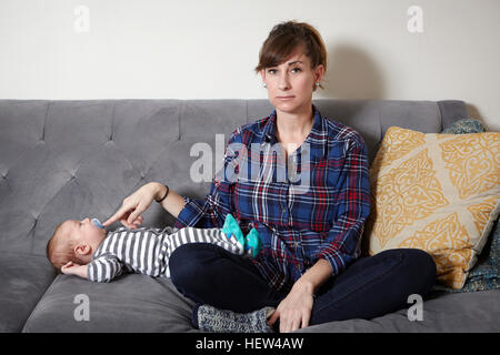 Mutter auf Sofa hält Baby junge Schnuller in Stockfoto