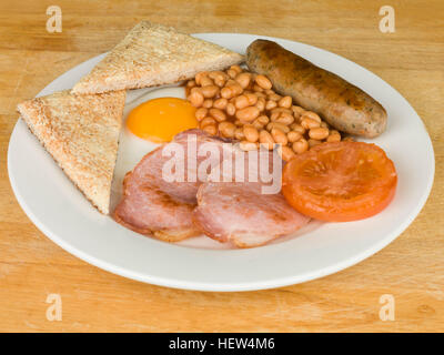 Englisches Frühstück Speck Ei, Würstchen, gebackene Bohnen und Tomaten auf einem weißen Teller serviert Stockfoto