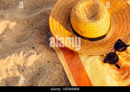 Sonnenbrille, Stroh Hut und Strand Handtuch auf sand Stockfoto