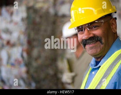 Porträt von Reifen männlichen Arbeitnehmer im harten Hut vor gestapelten Abfall an recycling-Anlage Stockfoto