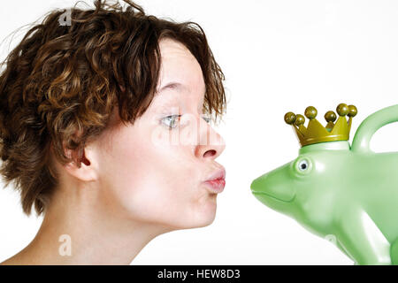 Junge Frau küssen Froschkönig Stockfoto