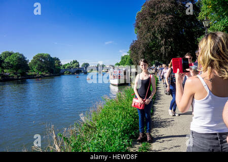 Eine junge Dame nimmt Foto von ihrem Freund von einem Mobiltelefon auf der Themse in Richmond, London. Stockfoto