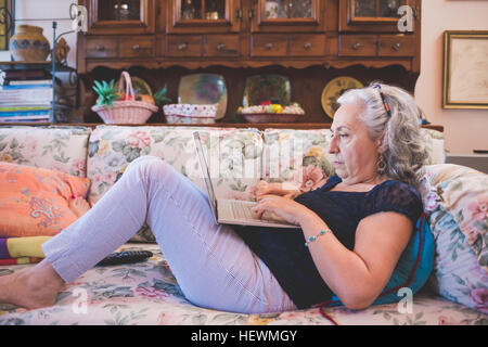 Frau liegt auf dem Sofa mit laptop Stockfoto