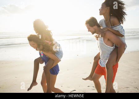 Junger Mann und Frau Huckepack Freunde in Strand Rennen, Cape Town, Südafrika Stockfoto