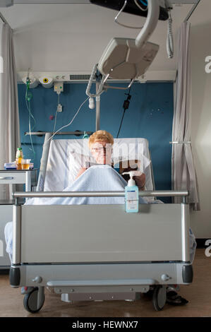 Patienten im Krankenhaus-Bett lesen Magazin Stockfoto