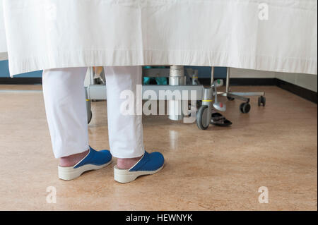 Füße von Krankenschwester hinter Krankenhaus Zimmer Vorhang Stockfoto