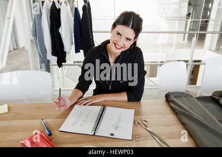 Frau skizzieren Modedesign, Blick in die Kamera Lächeln Stockfoto