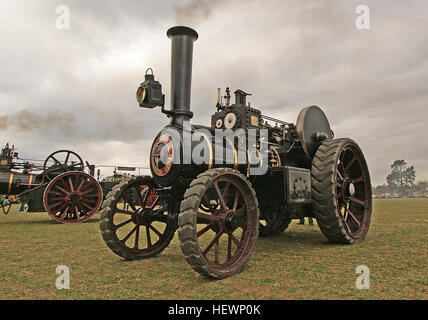 Die Burrell Traction Engine, eine dampfbetriebene Maschine, wird bei einer alten Landwirtschaftsrallye in Aktion fotografiert. Dieses historische Fahrzeug ist bekannt für seine rote Farbe und den robusten Dampfmotor und repräsentiert die Kraft und Innovation früherer Landmaschinen. Zugmaschinen wie diese waren für das Pflügen von Feldern und den Gütertransport im späten 19. Und frühen 20. Jahrhundert von entscheidender Bedeutung. Stockfoto