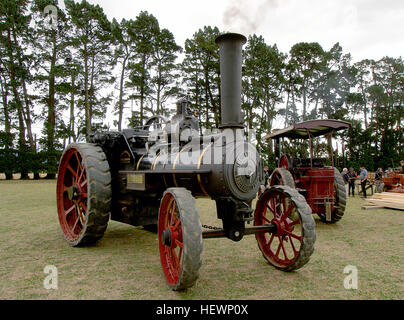 Dieses Foto zeigt einen Burrell Traction Engine, einen klassischen Dampfmotor aus der Ära der alten Landwirtschaft. Der rot gefärbte Motor wird bei einer Traktionsmotorenrallye in Aktion gehalten und spiegelt die historische Bedeutung dampfbetriebener Maschinen im landwirtschaftlichen Leben wider. Stockfoto