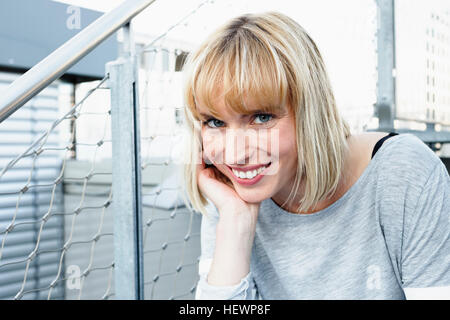 Porträt der blonde kurzhaarige Frau hand aufs Kinn Blick auf die Kamera zu Lächeln Stockfoto