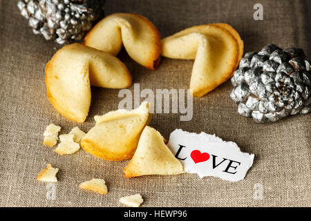 Cookies mit dem Wort Liebe geschrieben auf ein Blatt Papier und zwei silberne Ananas im Hintergrund wie Tortellini geformt. Horizontales Bild. Stockfoto