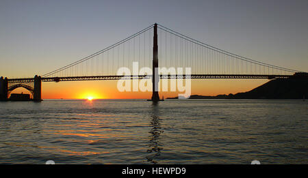 Dieses Foto zeigt die Golden Gate Bridge, aufgenommen während einer Bootstour bei Sonnenuntergang in San Francisco. Die Brücke ist ein berühmtes Wahrzeichen und bietet einen atemberaubenden Blick auf die Bucht und die Stadt, die oft bei Besichtigungstouren zu sehen sind. Stockfoto