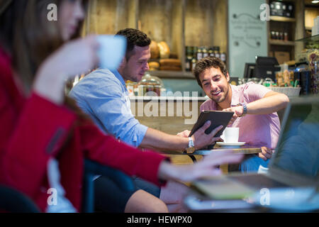 Männliche Freunde sitzen im Café auf digitale Tablet zeigen Stockfoto