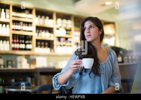 Junge Frau sitzt im Café suchen seitwärts Stockfoto