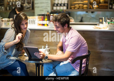 Junges Paar im Café Blick auf digital-Tablette Stockfoto