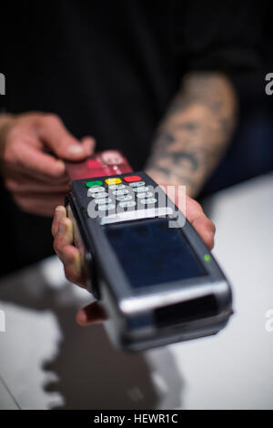 Schließen Sie oben von jungen mans Hände mit Kreditkarte Maschine Stockfoto