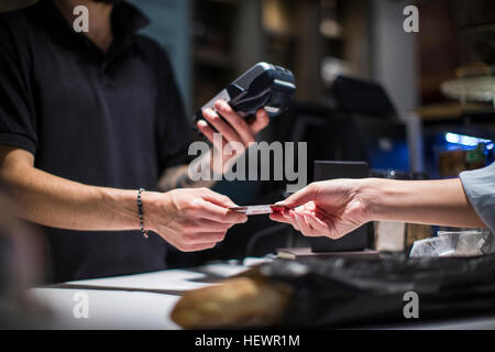 Nahaufnahme von Barista Übergabe Kreditkarte an Kundin Stockfoto