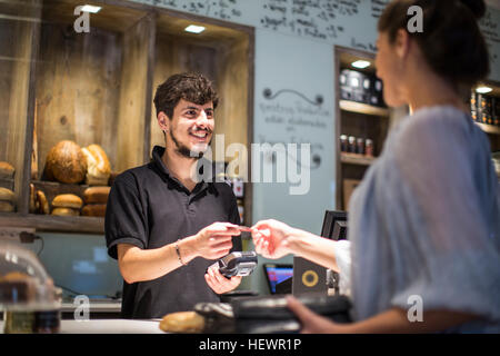 Barista Übergabe Kreditkarte an Kundin am Café-Schalter Stockfoto