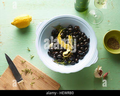 Draufsicht der Schale mit schwarzen Oliven mit Zitrone schälen auf Tisch Stockfoto