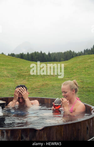 Junges paar entspannende im ländlichen Whirlpool mit Roséwein, Sattelbergalm, Tirol, Österreich Stockfoto