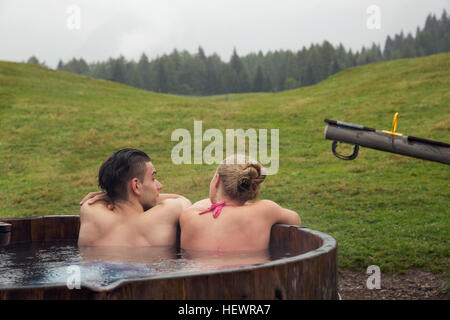 Rückansicht des jungen Paares zum Entspannen in ländlicher Whirlpool, Sattelbergalm, Tirol, Österreich Stockfoto
